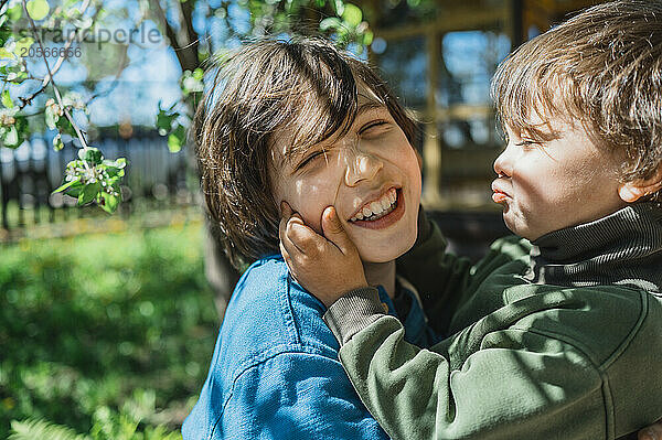 Cute boy embracing brother during summer in back yard