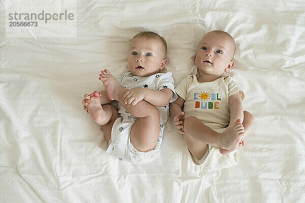 Cute twin brothers lying on bed at home