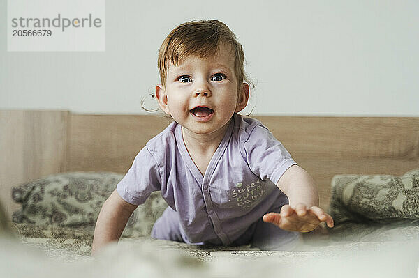 Smiling cute baby crawling on bed at home