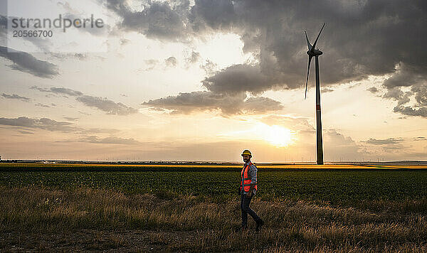 Engineer on wind field in front of sunset sky