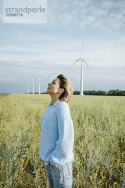 Woman with hands in pocket standing at field