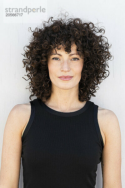 Confident beautiful woman with curly hair wearing black tank top