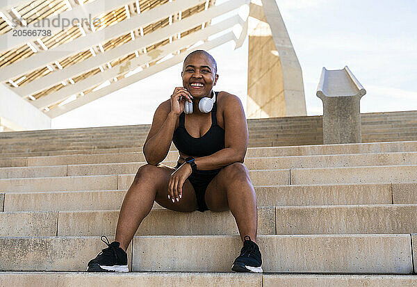 Happy sporty woman with headphones sitting on steps