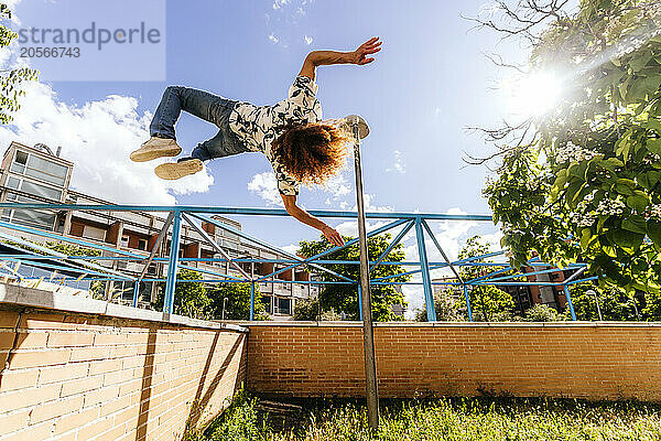 Carefree man performing parkour in park on sunny day