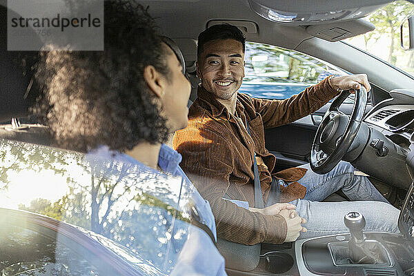 Happy young man sitting with girlfriend in car