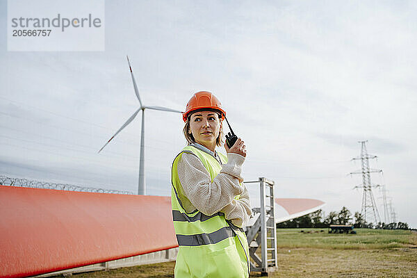 Engineer communicating through walkie-talkie at wind farm