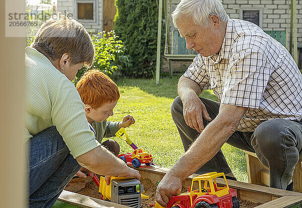 Grandfather and grandmother playing with grandson in back yard