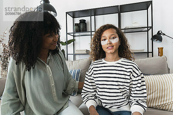 Smiling mother looking at daughter with beauty pads