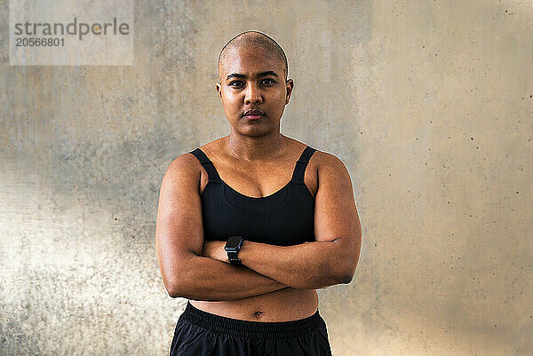 Muscular sporty woman with arms crossed in front of wall