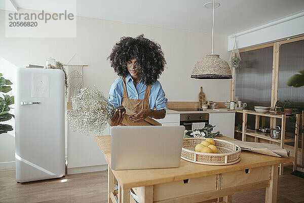 Florist examining bouquet in kitchen workspace