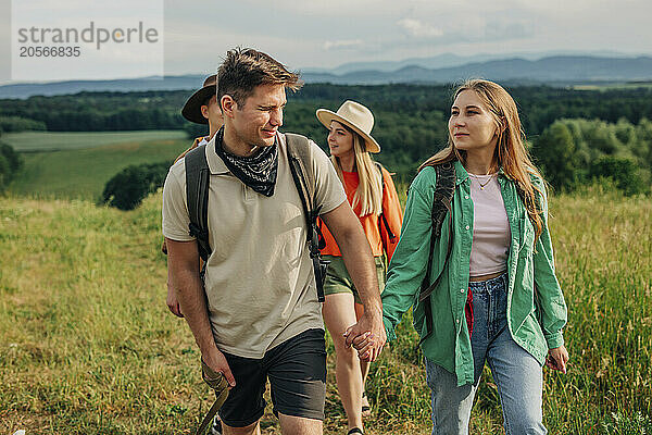 Young couple holding hands and hiking with friends on mountain