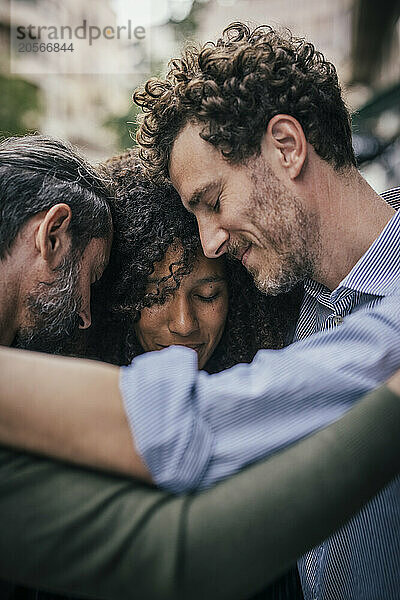 Smiling friends embracing each other at street