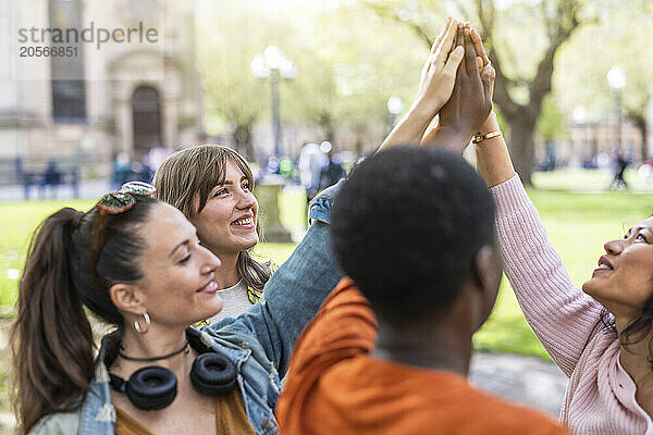 Smiling women with hands raised at park