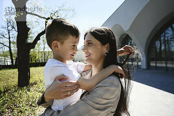 Smiling mother carrying son at park