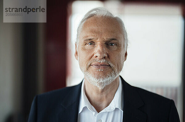 Confident senior businessman with white stubble at office