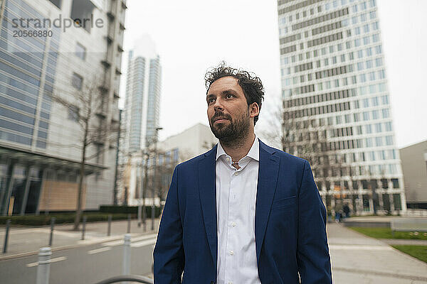 Businessman on footpath near modern skyscrapers in city