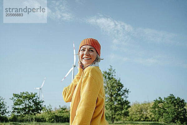 Cheerful woman standing near wind turbine at wind farm