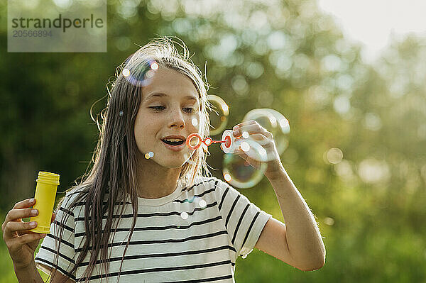 Excited girl blowing soap bubble