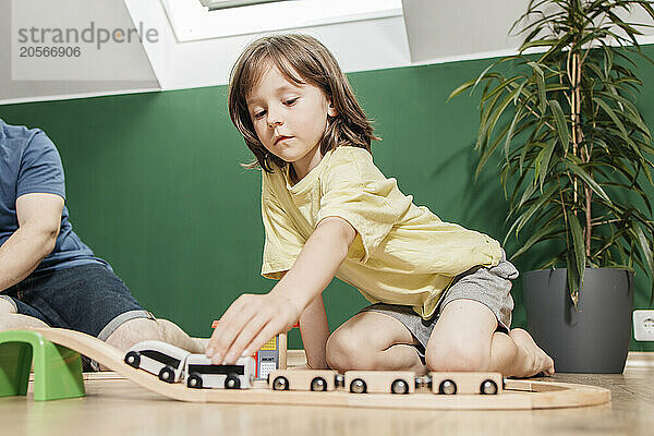 Cute boy playing with train toy with father at home