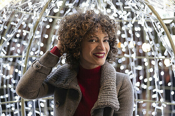 Smiling woman with curly hair in front of Christmas lights