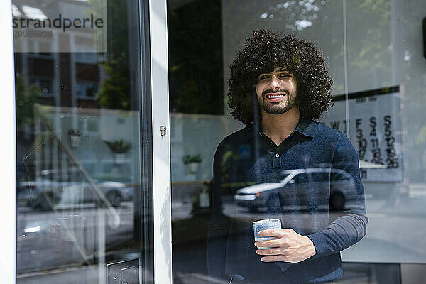 Smiling businessman with coffee cup looking out through window