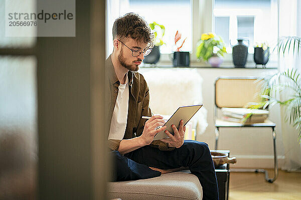 Young man using tablet PC sitting at home