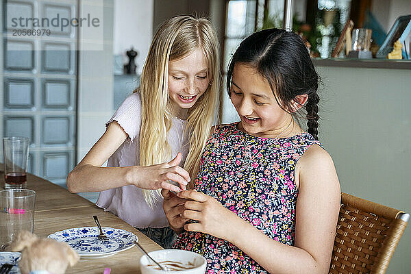 Happy multiracial girls playing at dining table in home