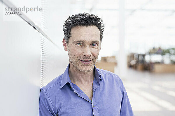 Handsome businessman leaning on wall in airport