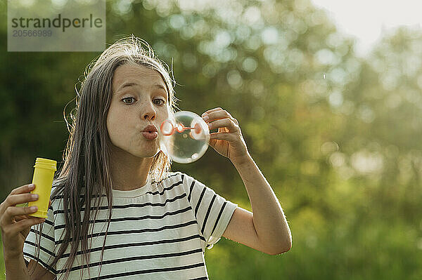 Playful girl blowing large soap bubble