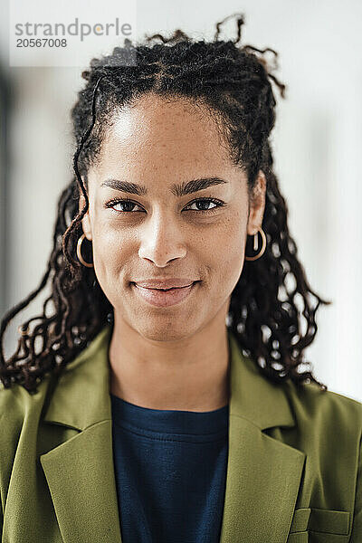 Confident young businesswoman wearing green blazer in office