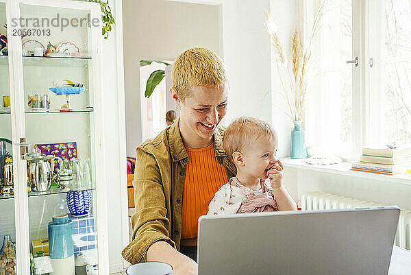 Happy working mother sitting with daughter at home