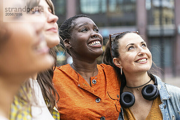 Happy multiracial female friends looking up