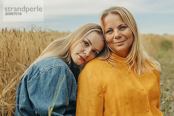 Blond hair woman leaning on mother at wheat field