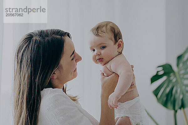 Happy mother holding baby boy at home