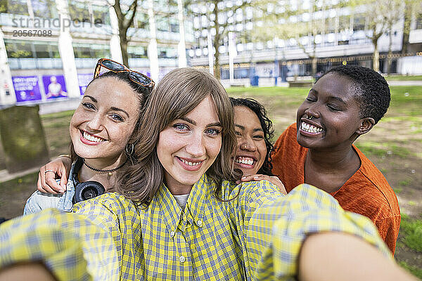 Happy young woman taking selfie with female friends at park