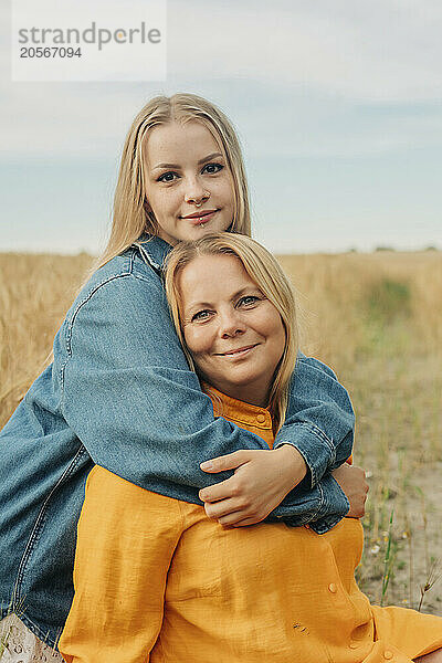 Blond hair woman with arm around mother at wheat field