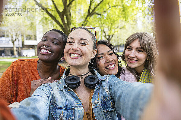 Happy woman taking selfie with female friends at park