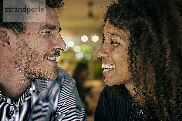 Laughing man and woman looking at each other sitting in cafe