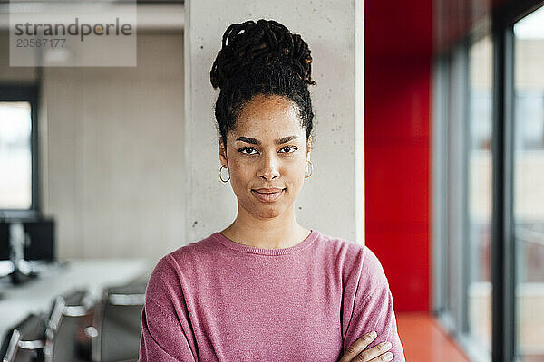 Confident young businesswoman standing in front of column at office