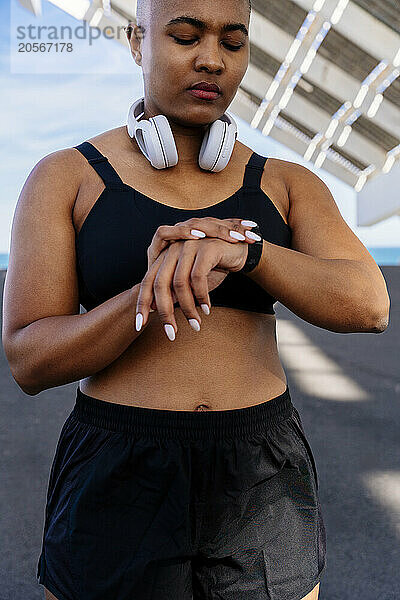 Sporty muscular woman checking smart watch on road