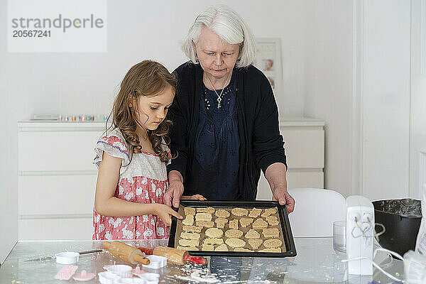 Girl preparing cookies with grandmother at home