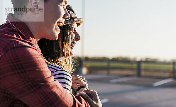 Cheerful young man with arm around girlfriend looking at view