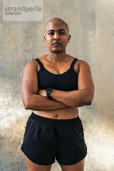 Muscular sportive woman in sports wear standing near wall