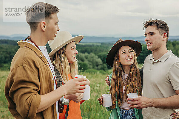 Group of friends discussing and holding coffee cup at mountain in Poland