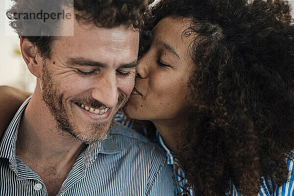 Woman with curly hair kissing boyfriend at cafe