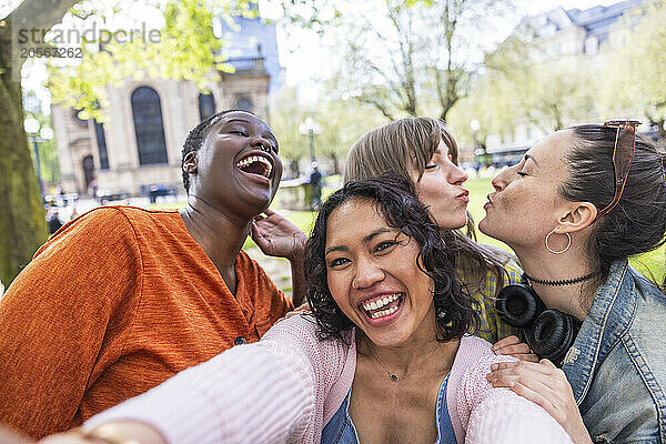 Cheerful woman taking selfie with female friends at park