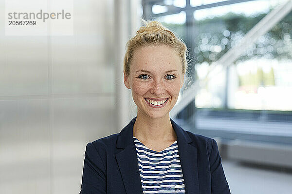 Happy businesswoman wearing blazer in airport lobby