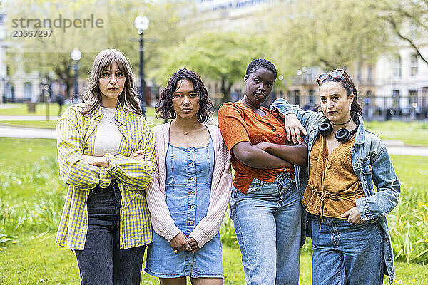 Confident female friends standing side by side at park