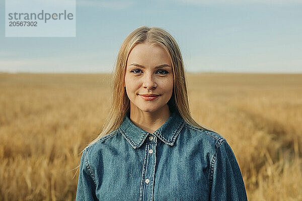 Young woman with piercing in denim shirt at wheat field