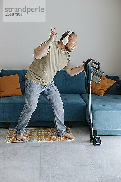 Man listening to music and doing housework in living room at home